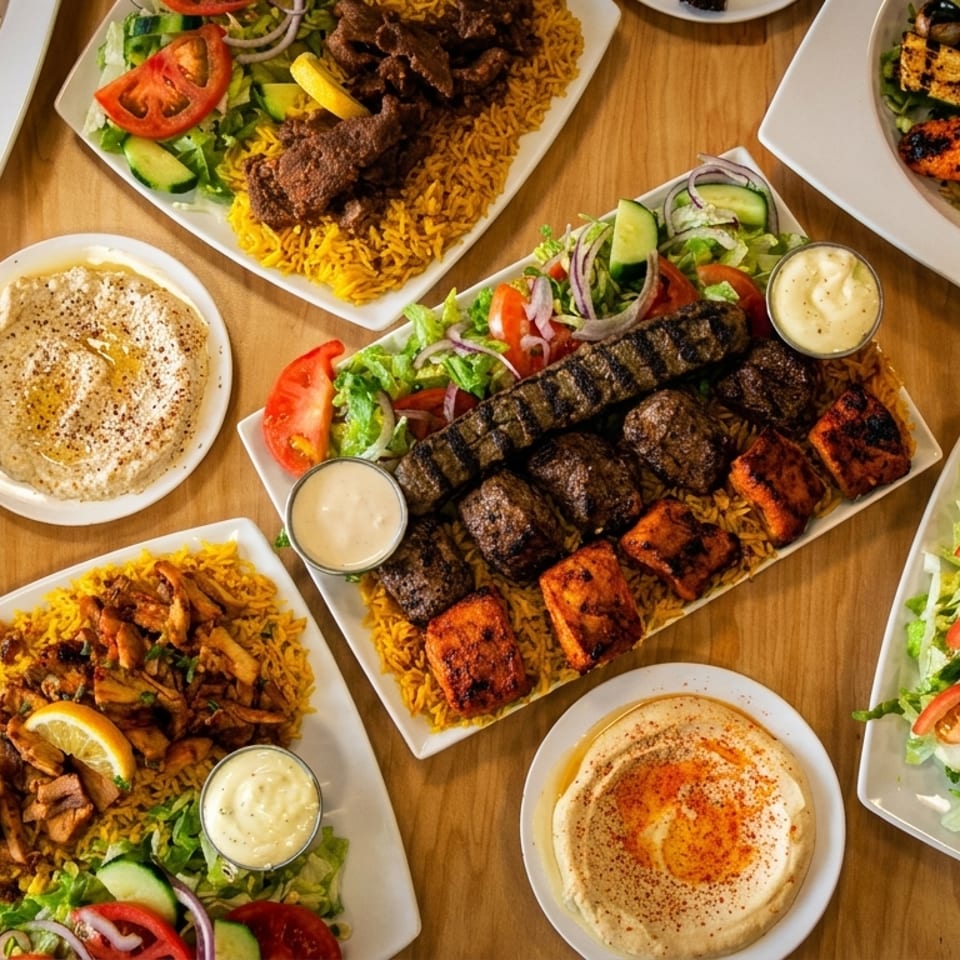 Overhead spread of Middle Eastern dishes featuring grilled meats, rice, salads, hummus, falafel, and shawarma on a wooden table.
