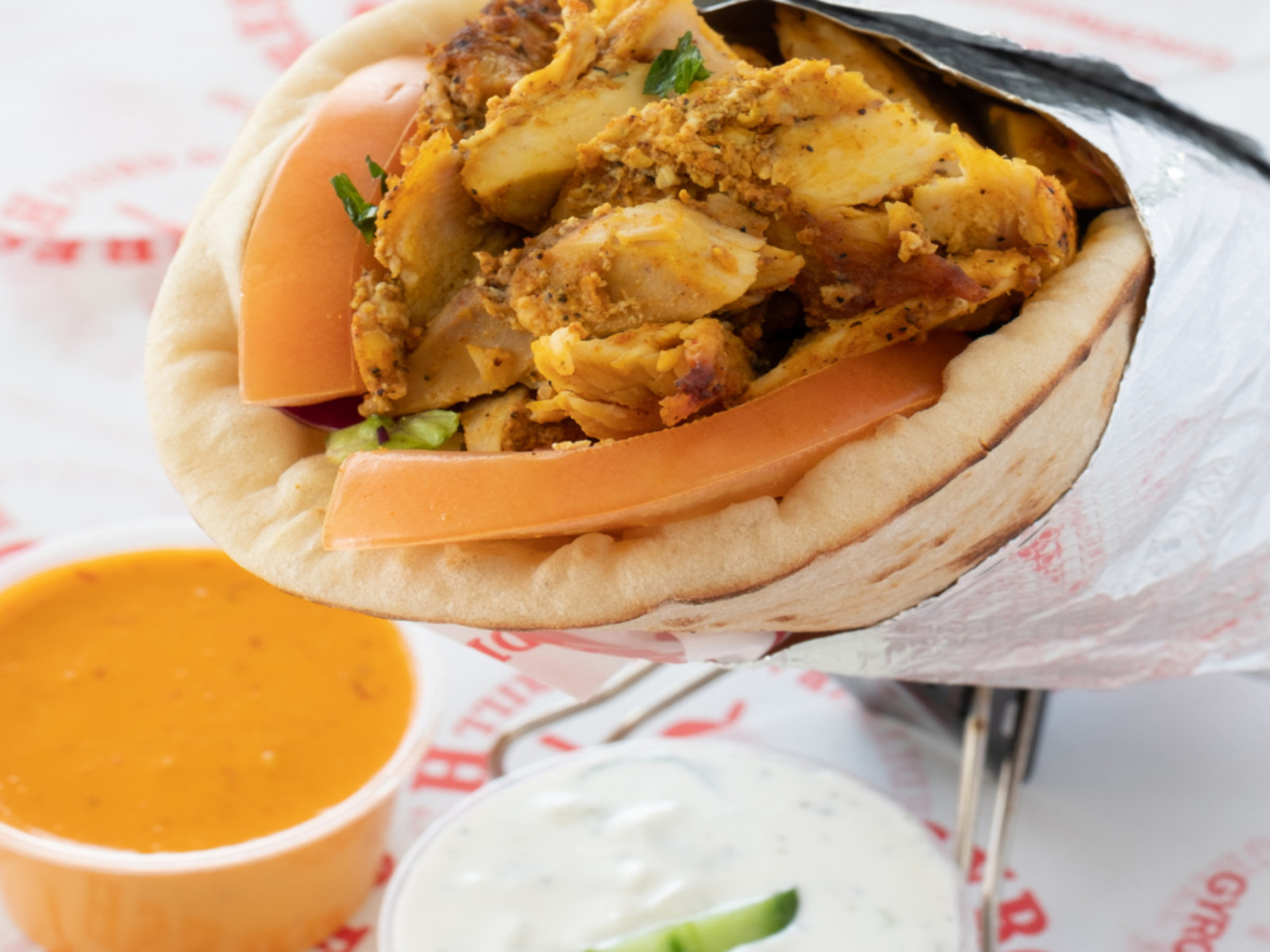 Shawarma Wrap (1) A large pita wrap generously filled with shredded spit‑roasted lamb & beef, chicken shawarma, or your choice of protein. It’s stuffed with lettuce, tomatoes, onions, and slathered in tzatziki or garlic sauce,